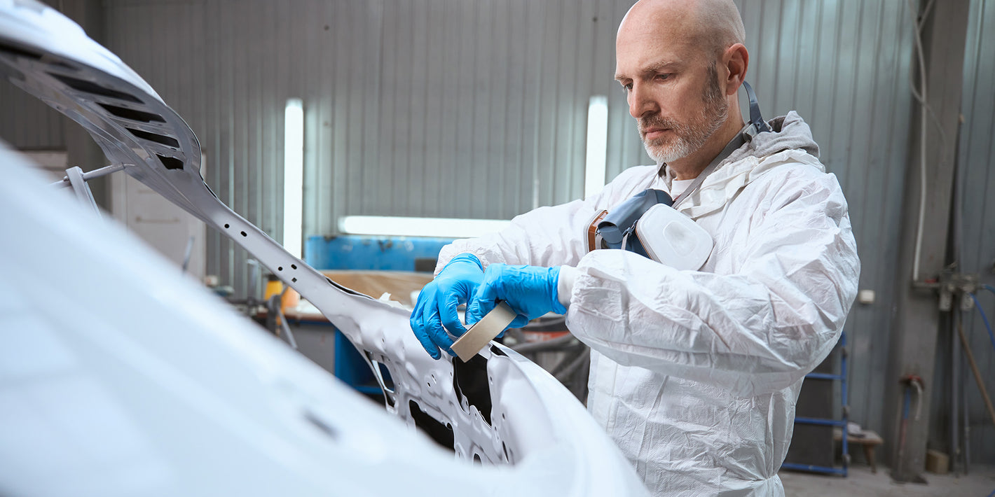 Man Applying Masking Tape To Car Body Panel